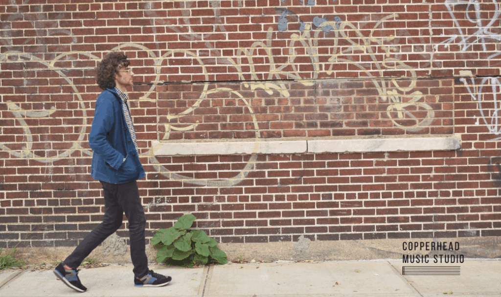 Ben walks in front of the brick wall